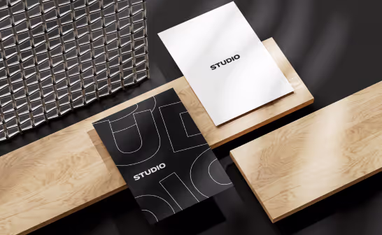 Printed brochures and a poster from the Studio identity, laid on wood